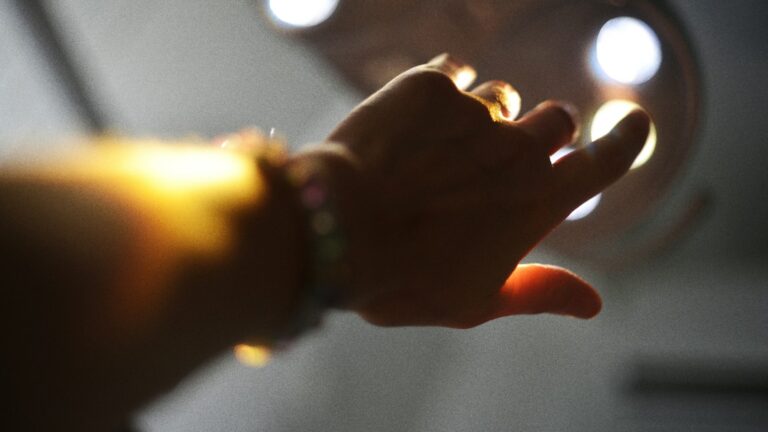 A hand reaching out towards a cluster of warm bright lights in a dark room